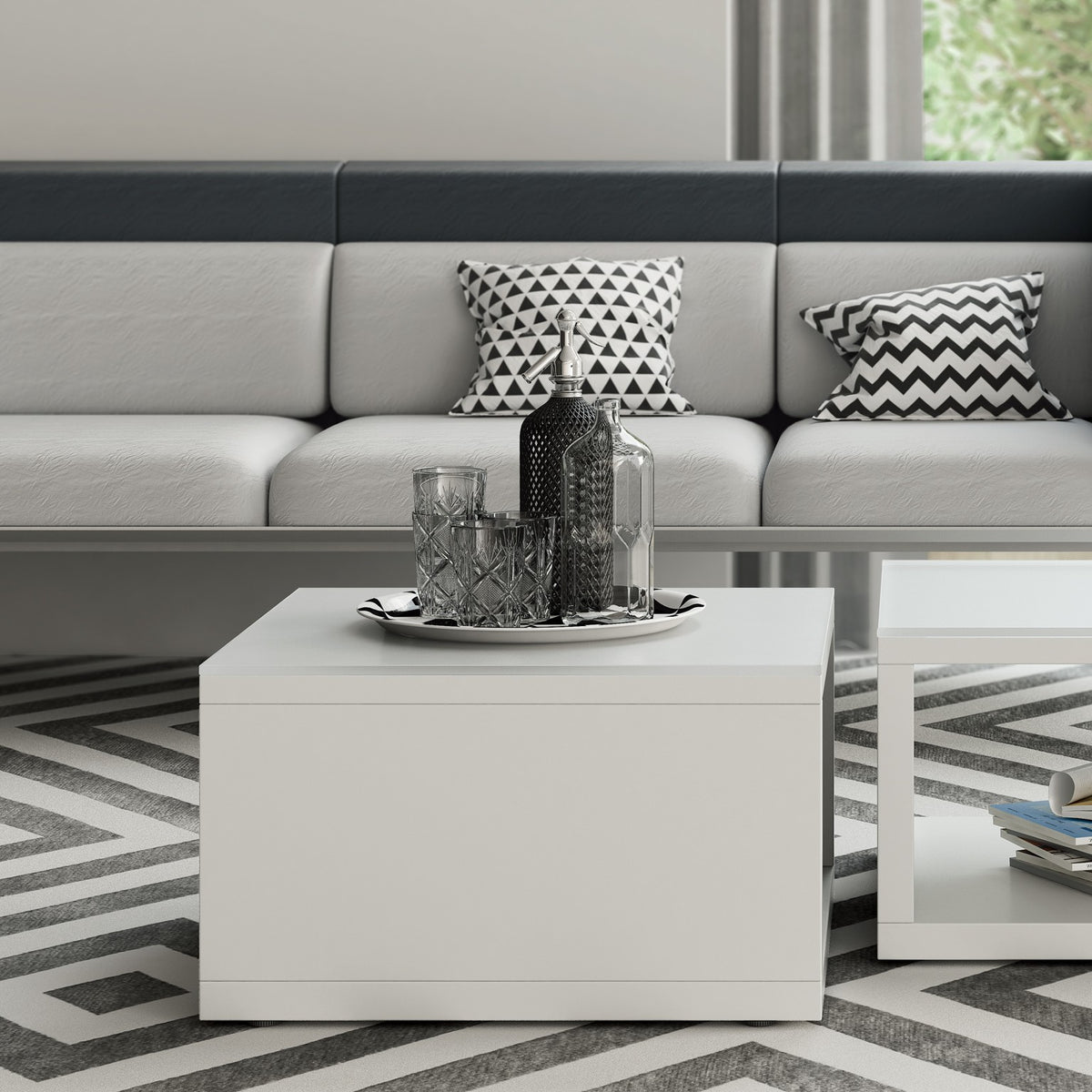 Tavolino ASSET in melaminico bianco con struttura pannellata, davanti a un divano in un'area lounge