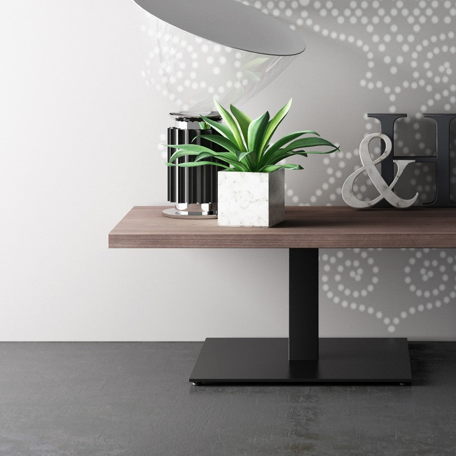 Tavolino rettangolare Frezza con piano in legno scuro e base quadrata nera, accanto a un divanetto blu