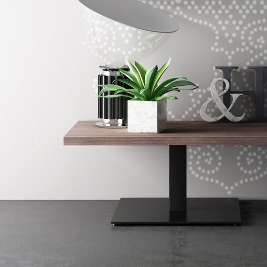 Tavolino rettangolare Frezza con piano in legno scuro e base quadrata nera, accanto a un divanetto blu