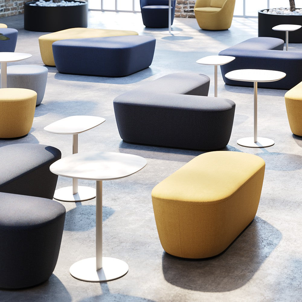 Tavolini RADAR Frezza bianchi in una grande sala d'attesa con pouf colorati
