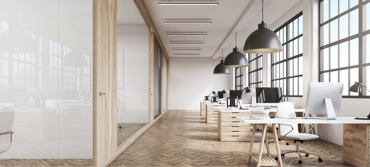 Open space con pareti vetrate e profili in legno, grandi finestre e scrivanie in legno
