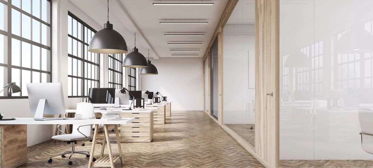 Open space con pareti vetrate e profili in legno, grandi finestre e scrivanie in legno