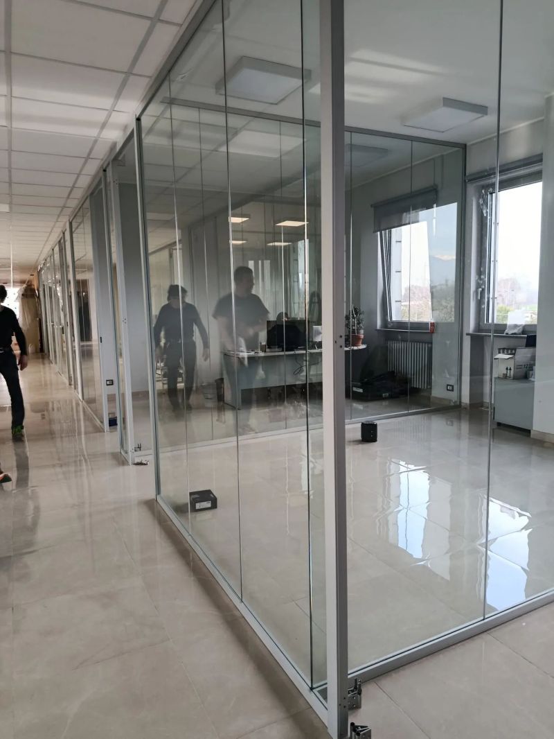 Pareti vetrate modulari che dividono gli uffici lungo un corridoio