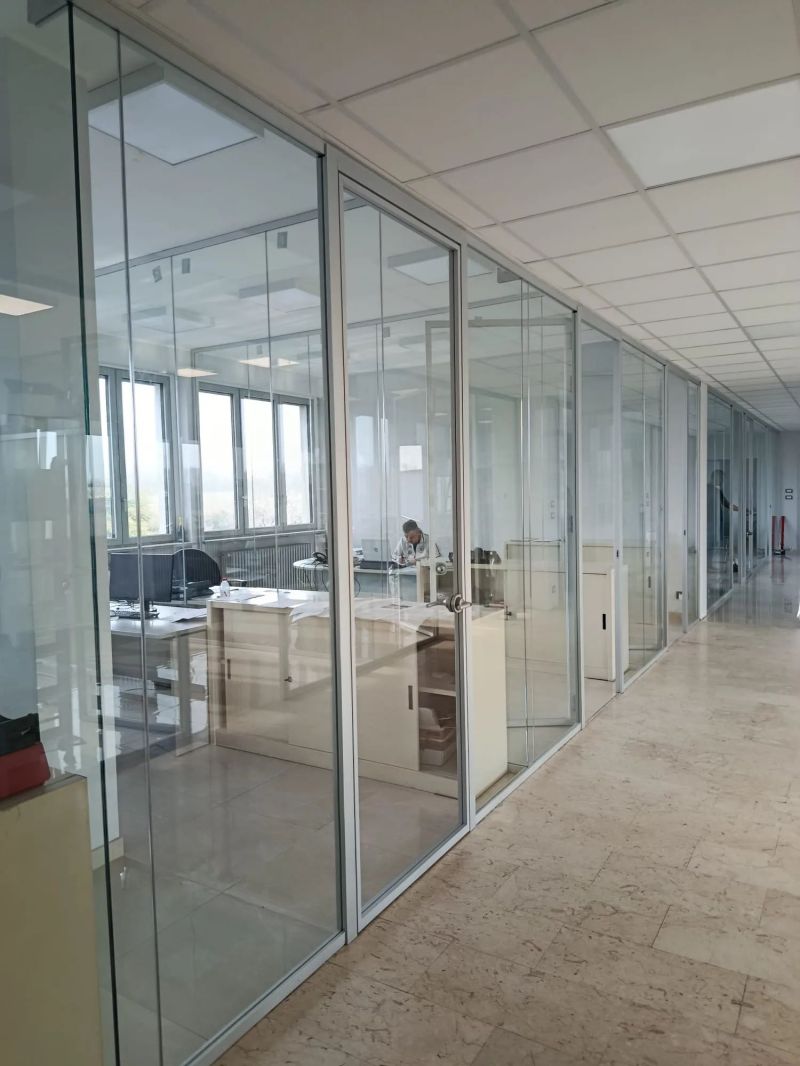 Fila di pareti vetrate modulari con porta a battente in un ufficio