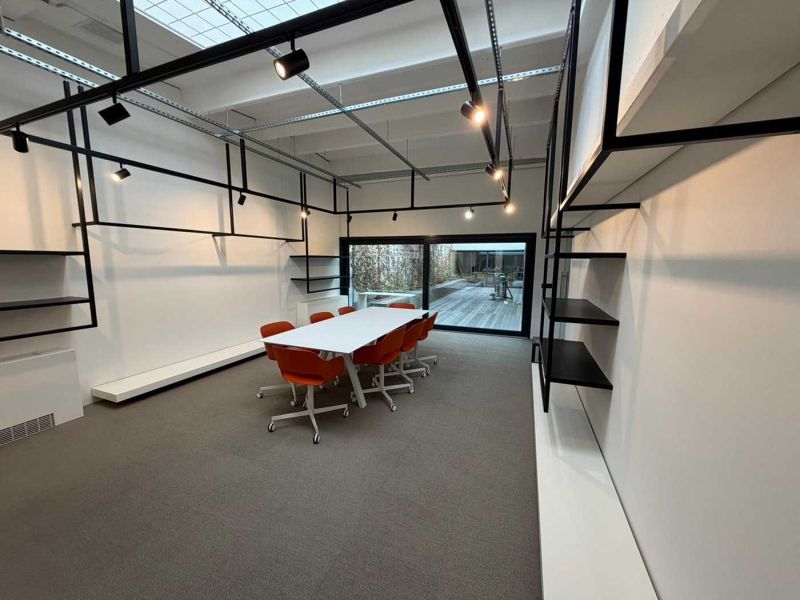 Sala dello showroom con struttura in ferro nero, faretti e sedie arancioni