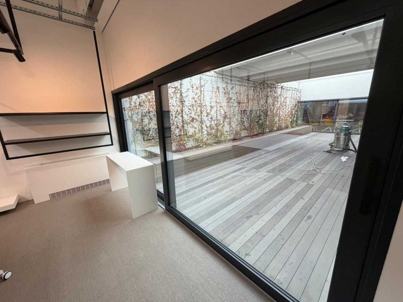 Grande vetrata scorrevole dello showroom sul patio con pavimento in legno